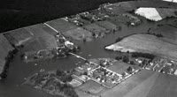 A black and white aerial photo of houses in the water.