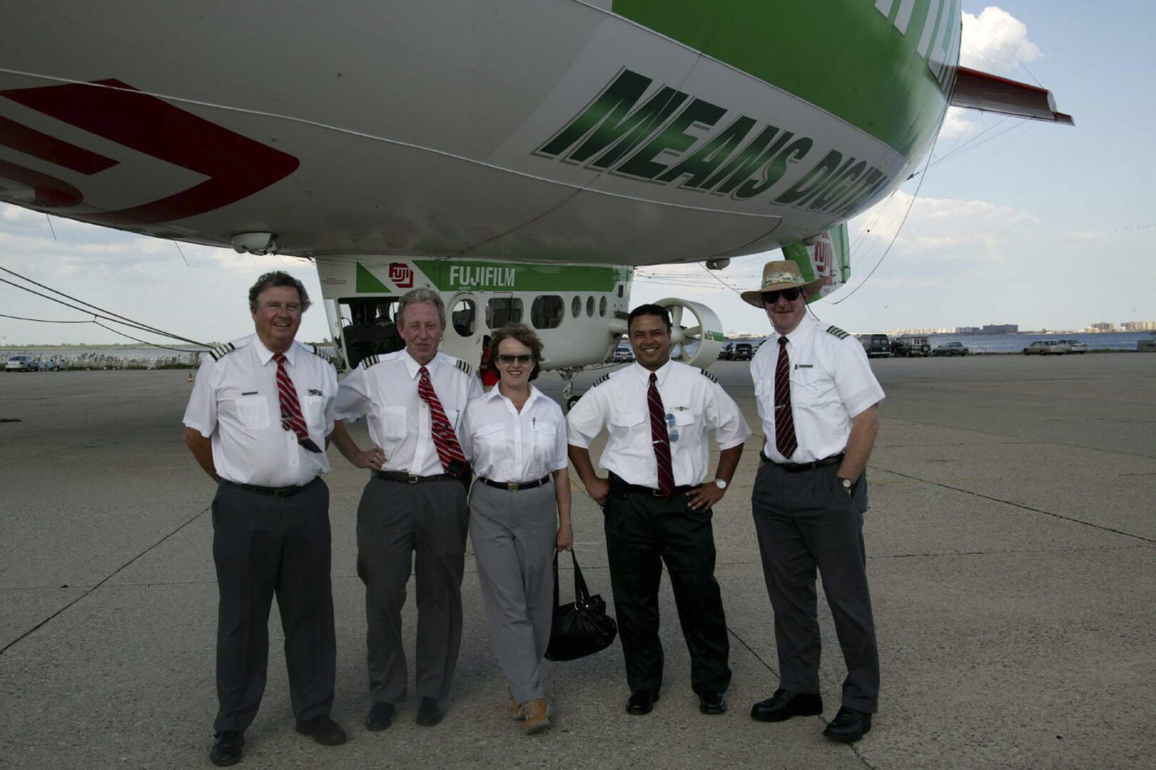 A group of people standing under an airplane.