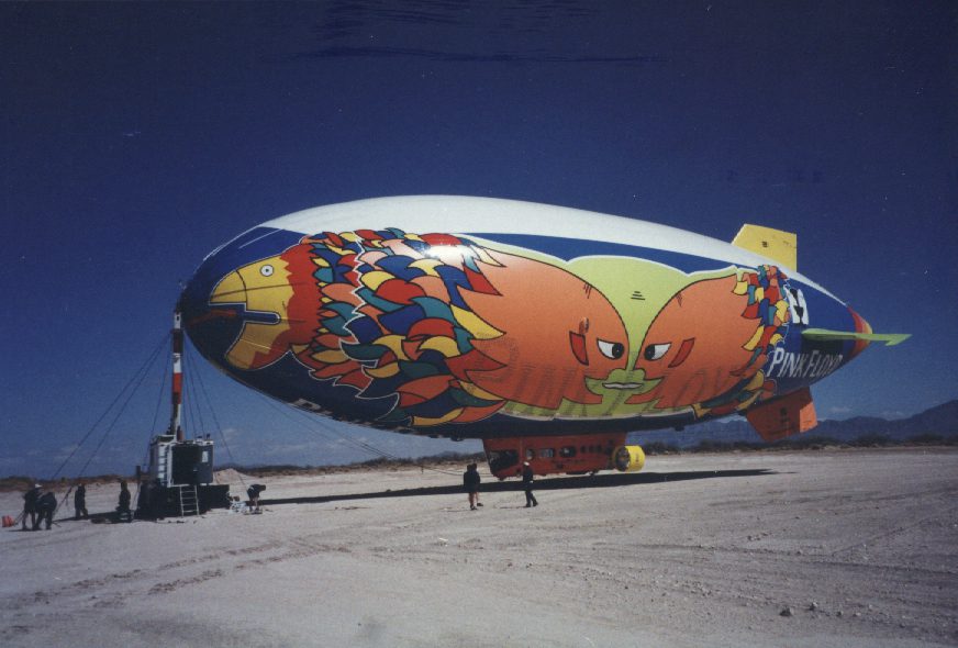 A large colorful airship sitting on top of an airport runway.